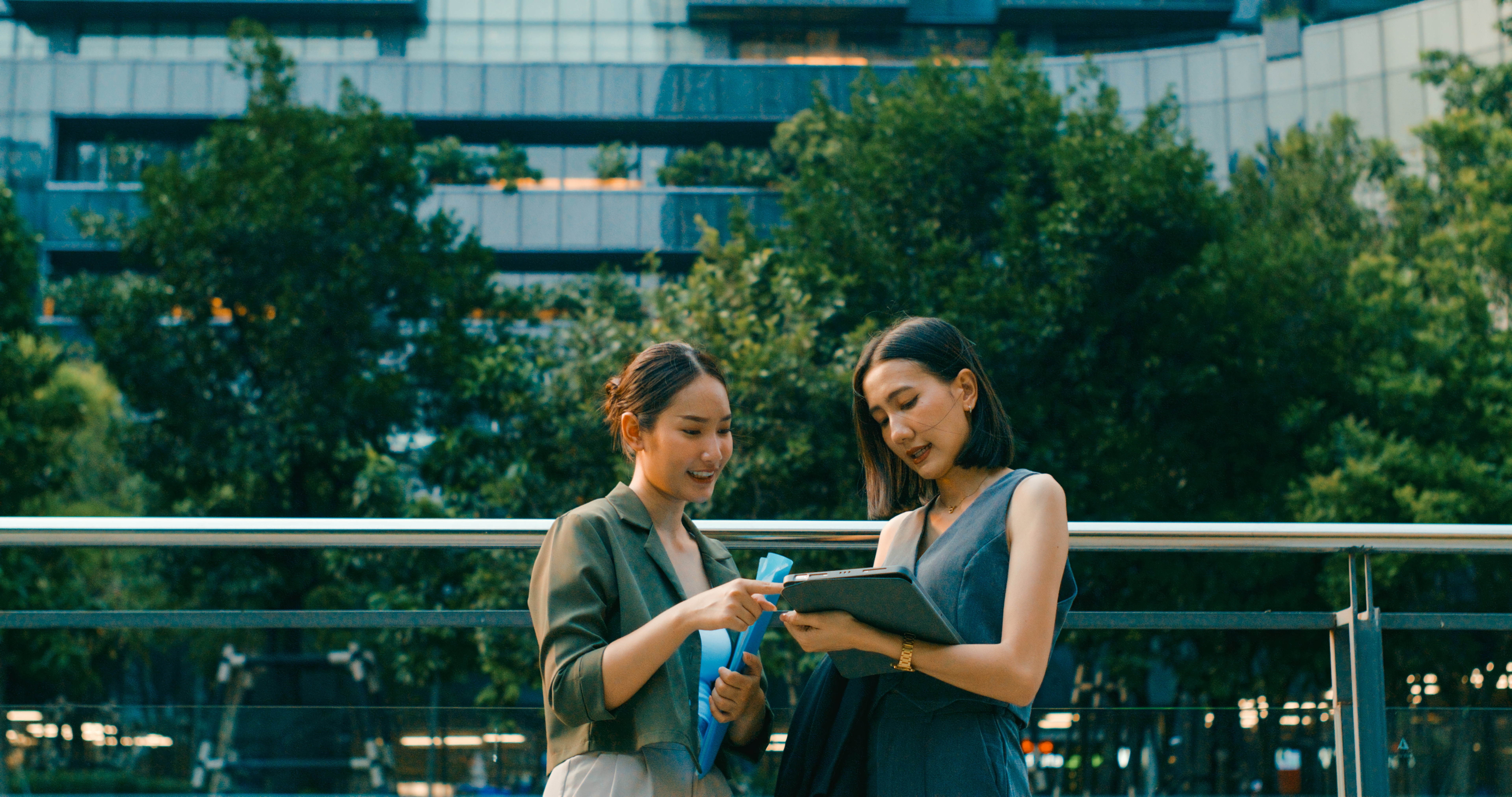 Duas mulheres em frente à um prédio repleto por natureza