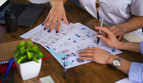 Imagem de duas pessoas reunidas e mexendo em documentos em uma mesa de escritório