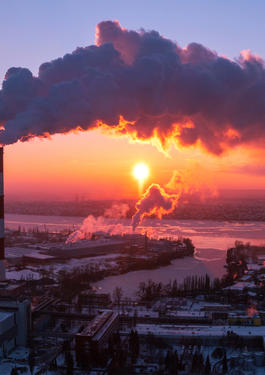 Imagem de uma cidade vista de longe, com duas chaminés industriais em foco