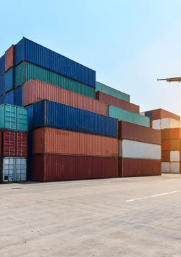 Containers em porto com avião sobrevoando.