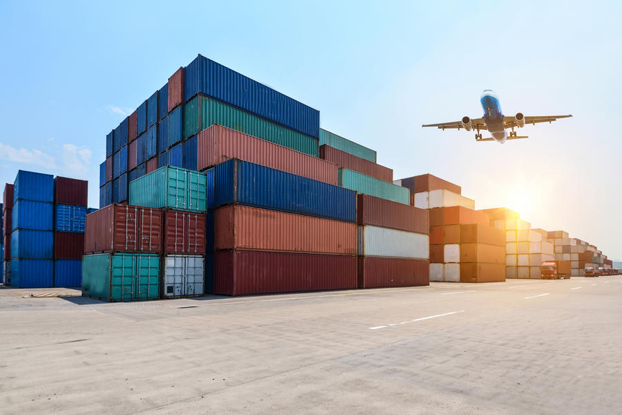 Containers em porto com avião sobrevoando.