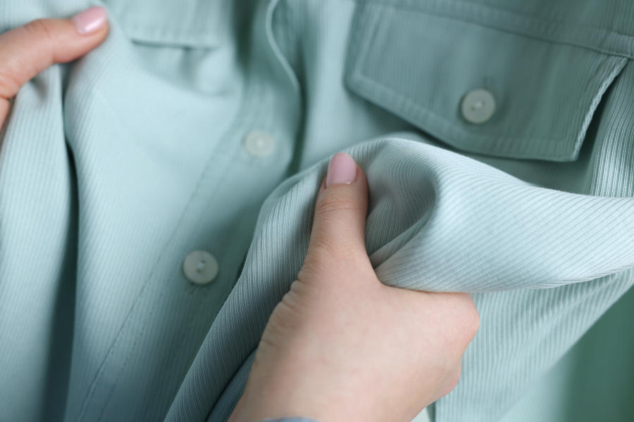 Mãos segurando camisa verde claro.