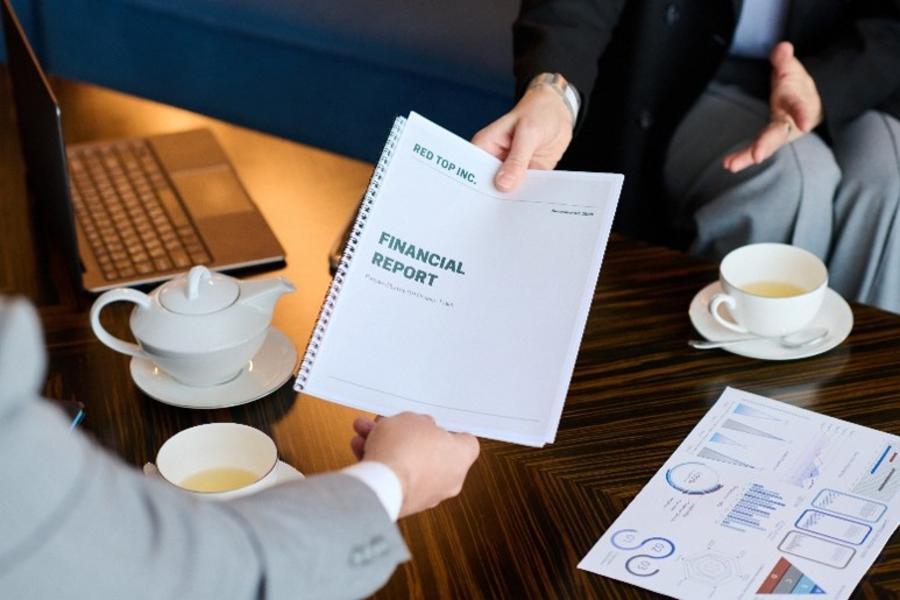 Pessoa em uma reunião entregando um documento a outra.