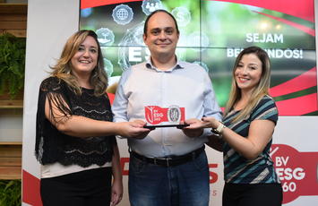 Imagem de três pessoas segurando o prêmio do selo BV ESG 360 com um fundo temático